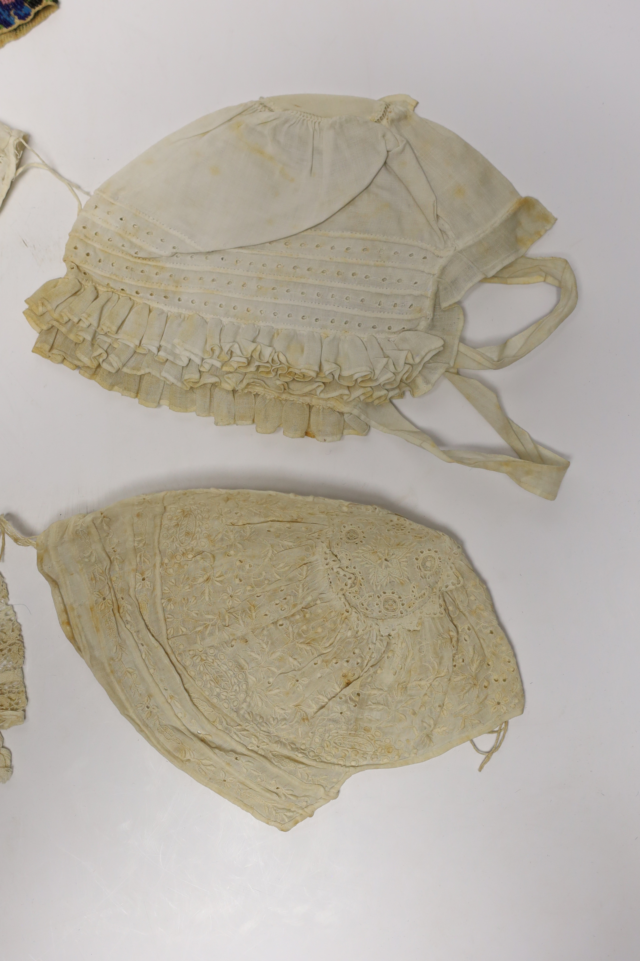 Seven baby bonnets, late 18th / 19th century, including a fine bobbin lace bonnet and unusual silk knitted and multi coloured floral designed beaded bonnet